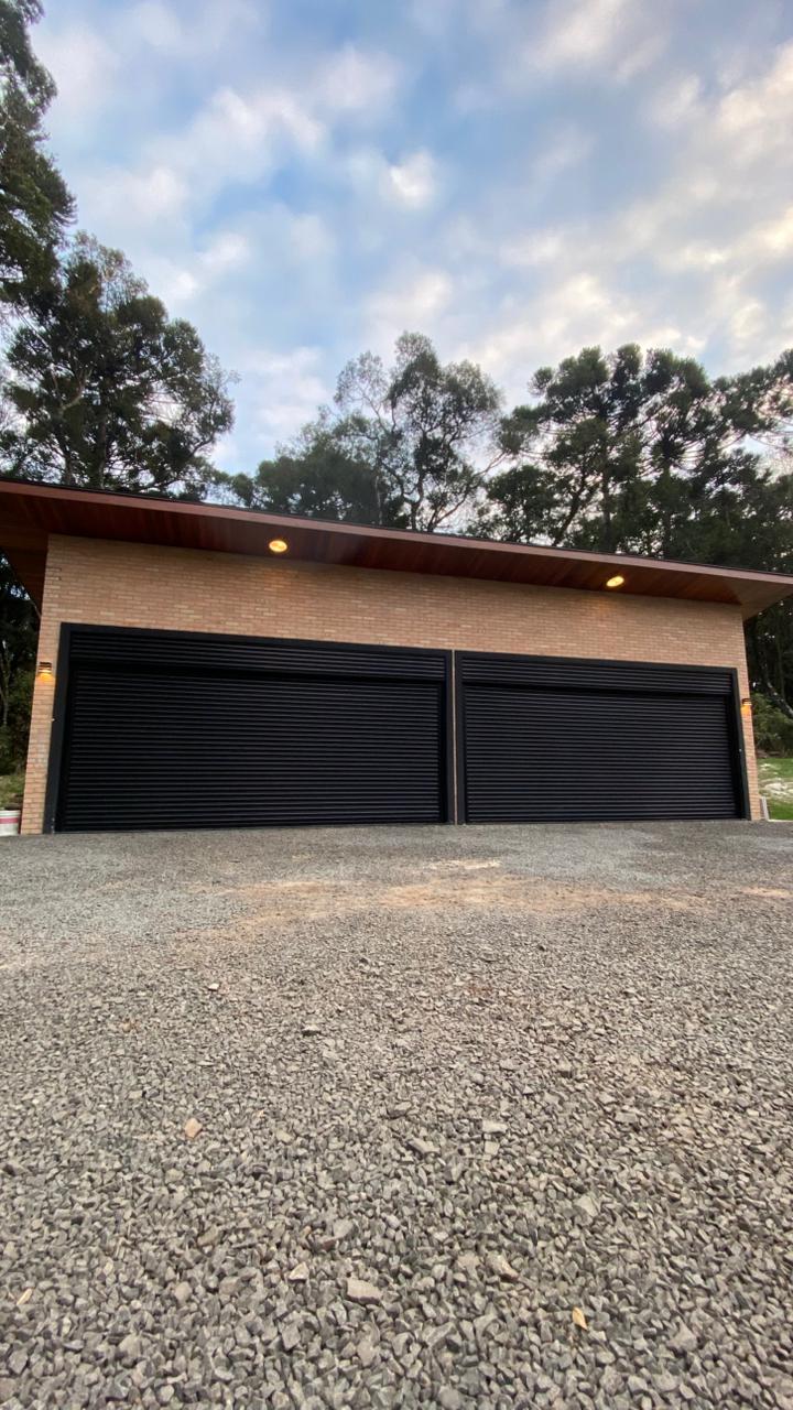 Fachada com duas portas de enrolar pretas automatizadas fabricadas pela Condor Metalúrgica
