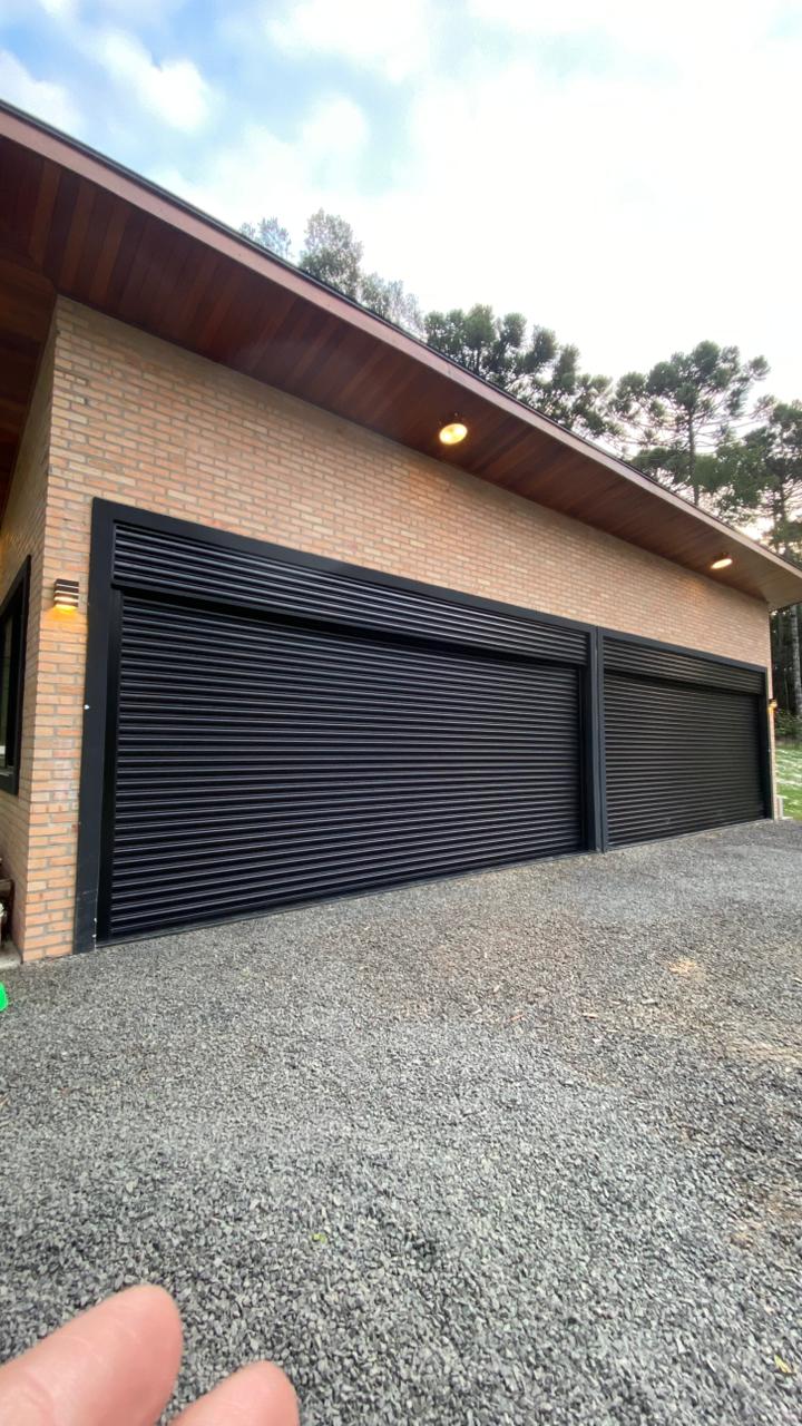 Vista lateral de portas de enrolar pretas automatizadas instaladas em garagem de alvenaria